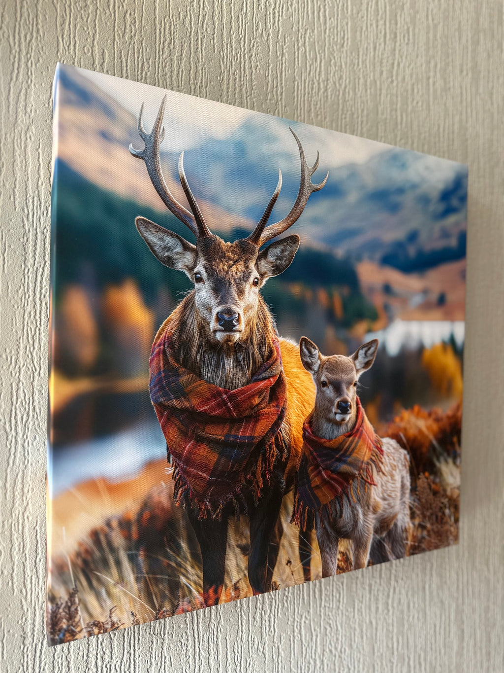 Two deer wearing plaid scarves against a mountainous landscape