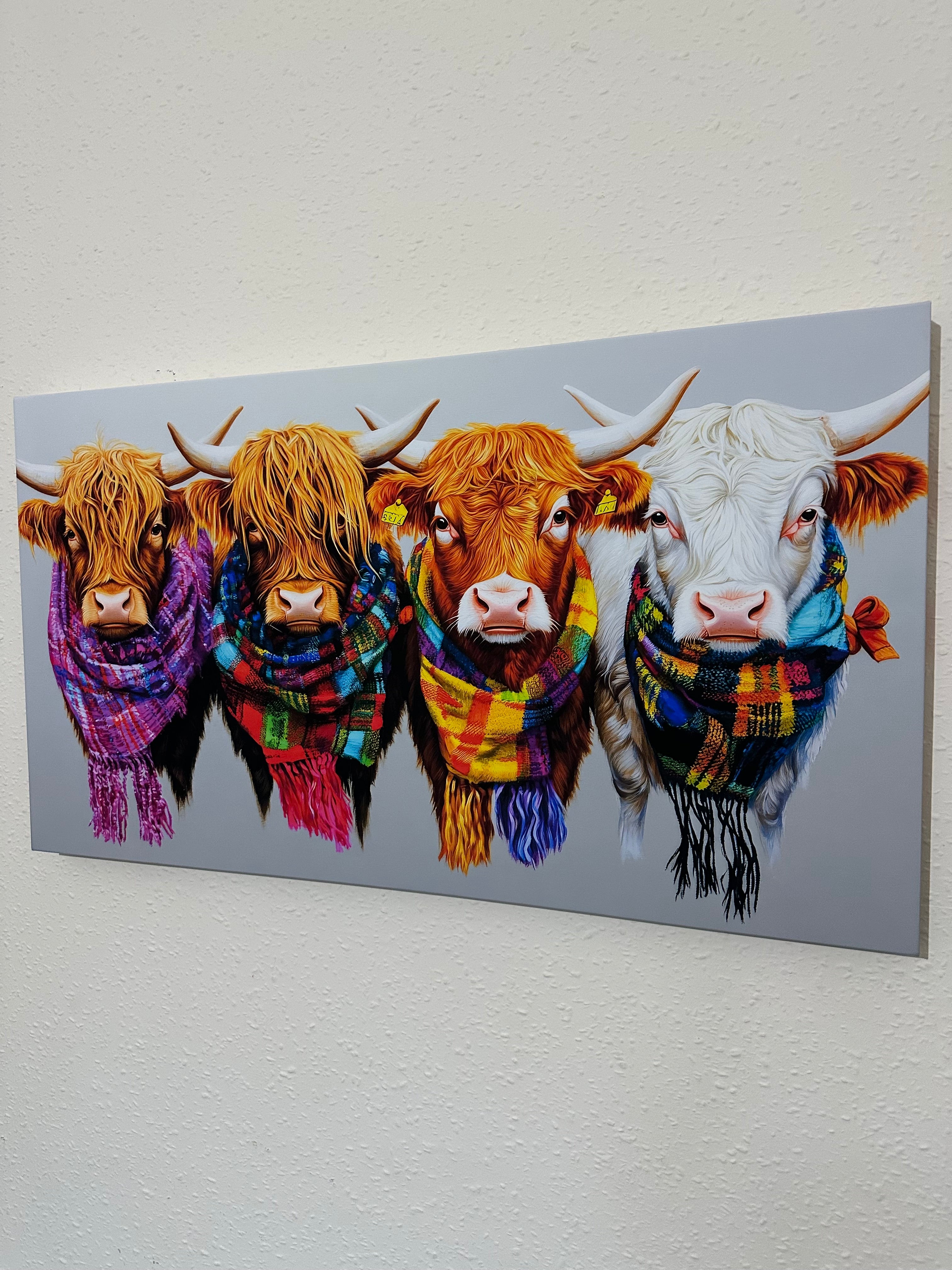 Wall art with four cows wearing colourful scarves 