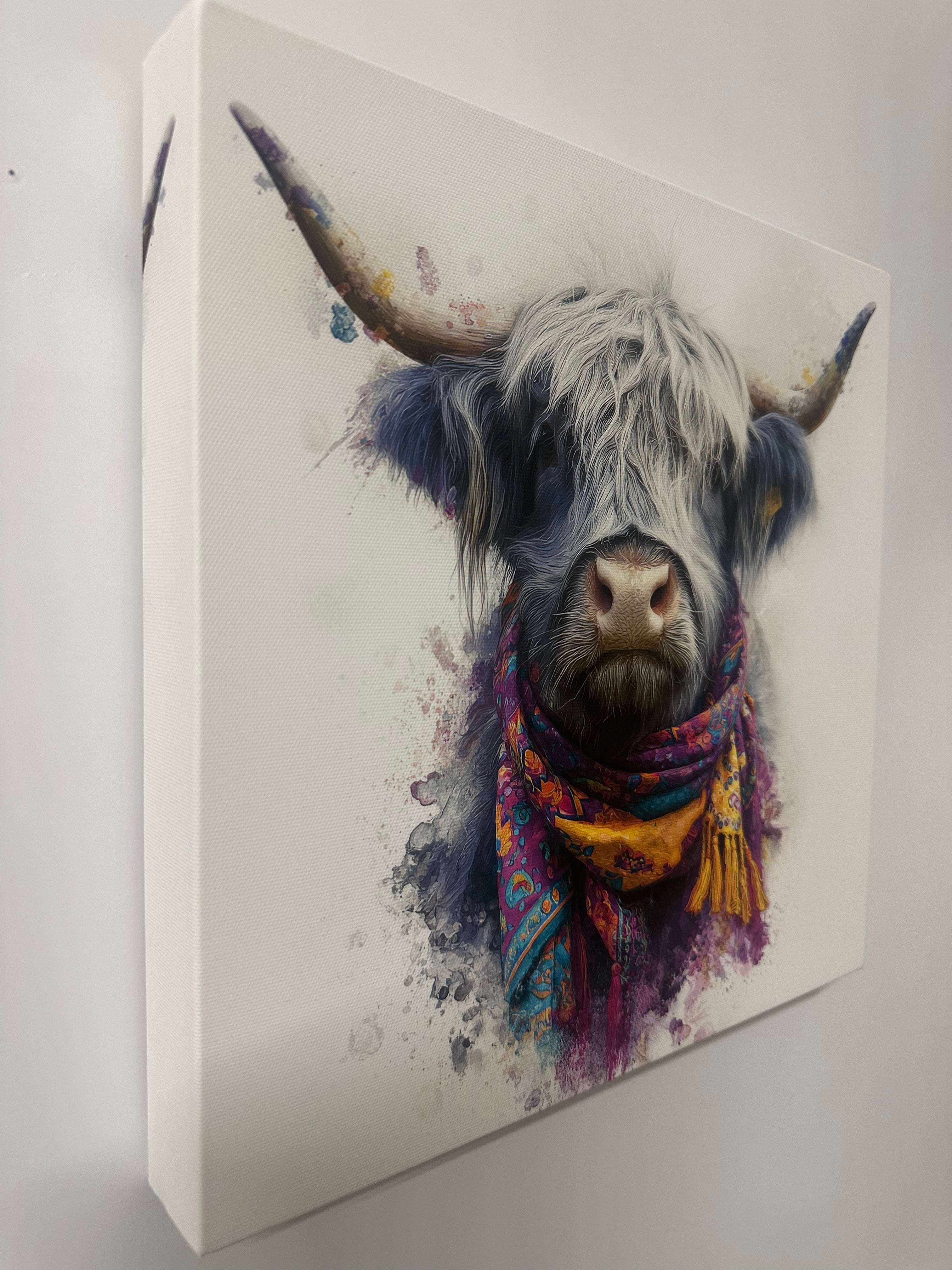 Colourful canvas wall art of a highland cow wearing a multicoloured scarf on a white background