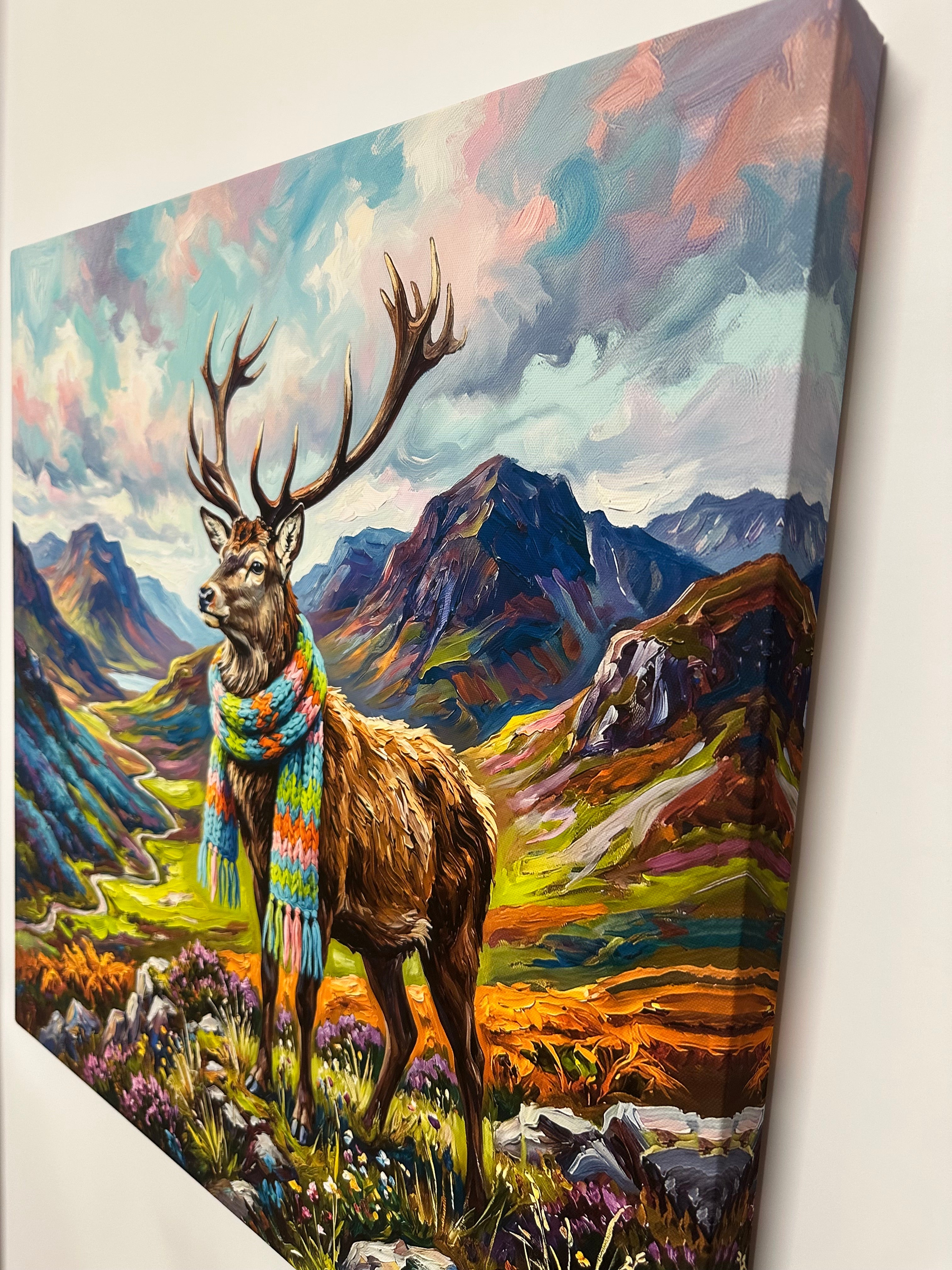 Canvas print of a deer with antlers wearing a colorful scarf against a mountainous landscape.