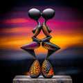 Abstract sculpture with colorful patterns on a reflective surface against a vibrant sunset sky.